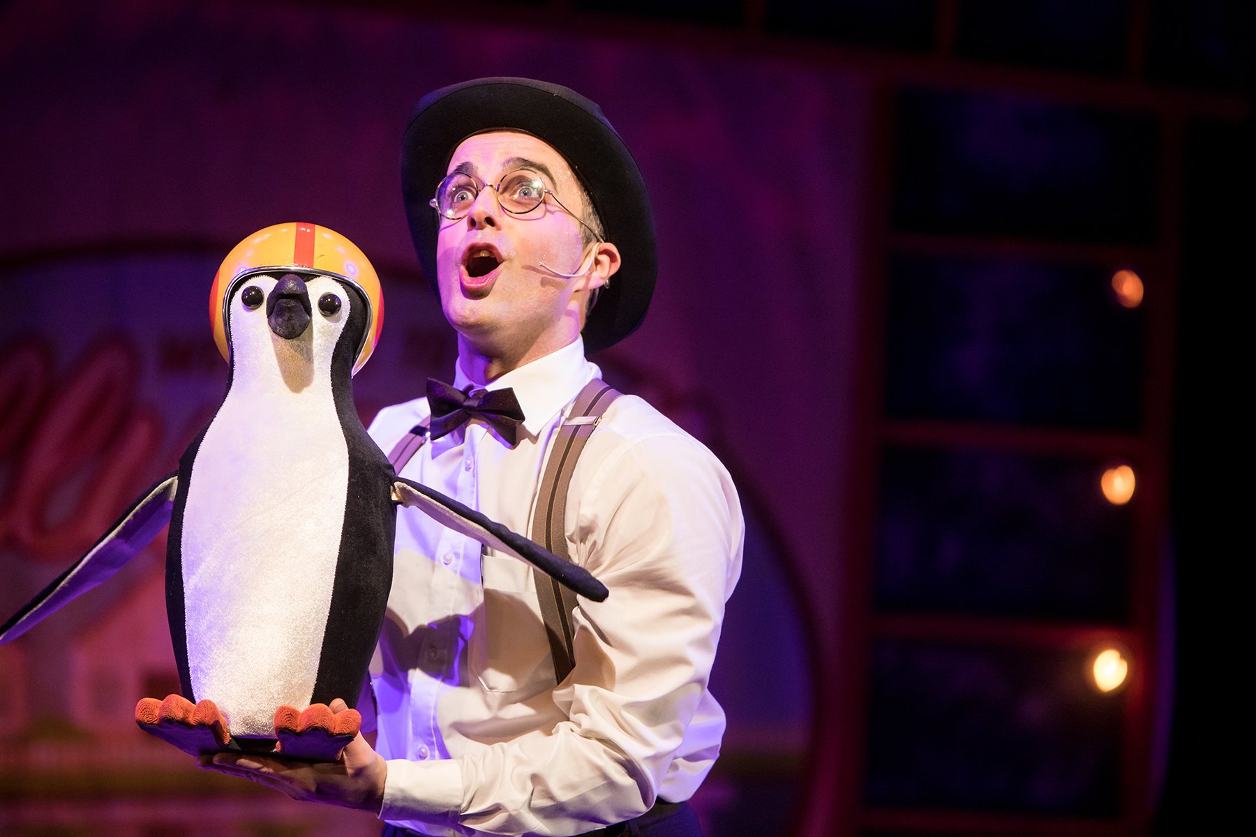 Man holding a penguin puppet with helmet on