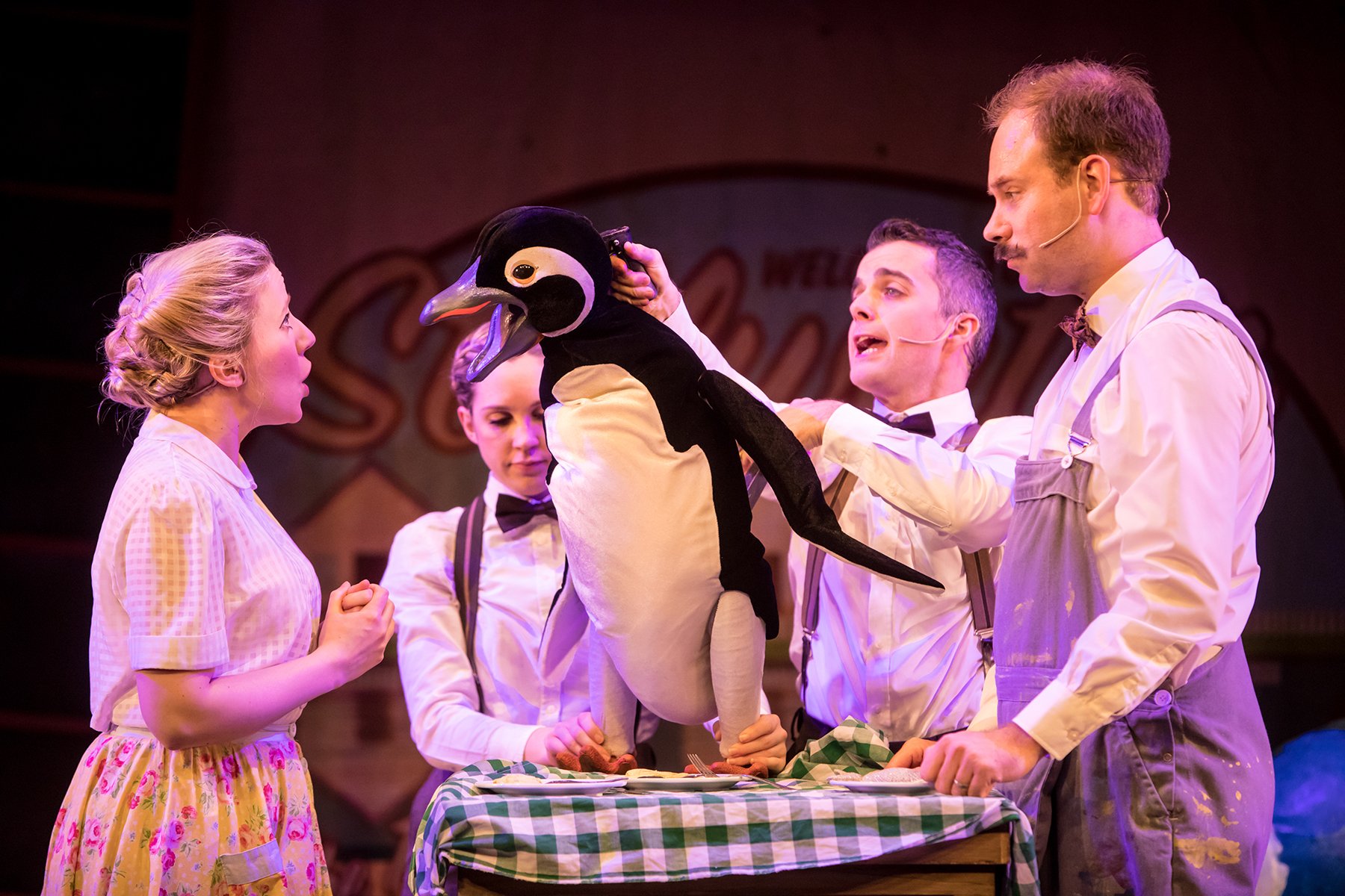 four people stood around a Penguin puppet
