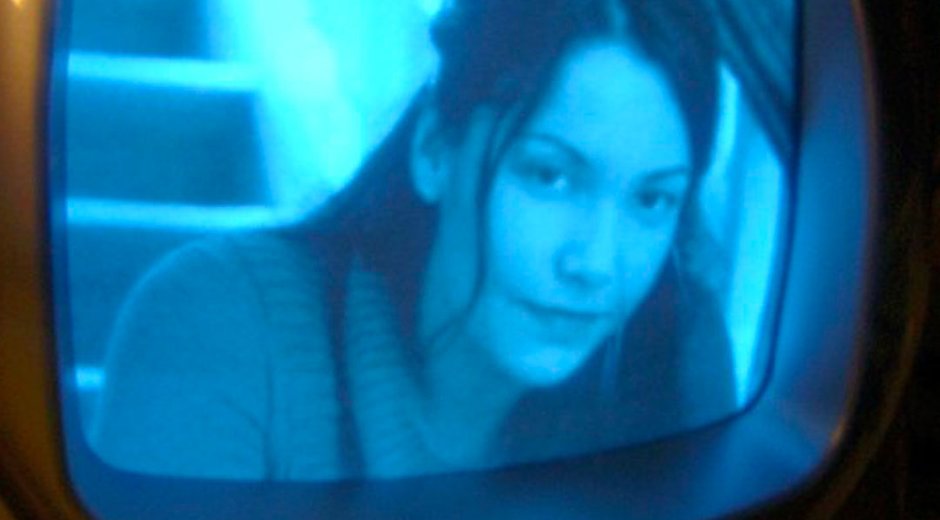 Alt text:  Promotional image showing a close-up of a person displayed on the screen of a vintage CRT television. The image is tinted in blue tones, with the television frame visible around the screen, creating a retro film and television aesthetic.