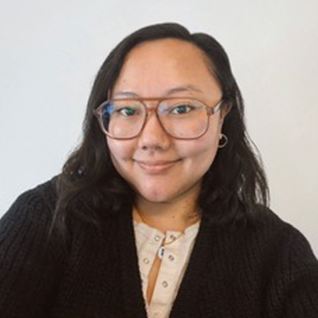 This image is a color head-and-shoulders portrait of a person positioned against a plain, light-colored background.