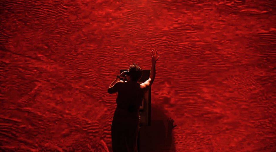 A single person stands near the center of the image, viewed mostly from behind and slightly in silhouette.