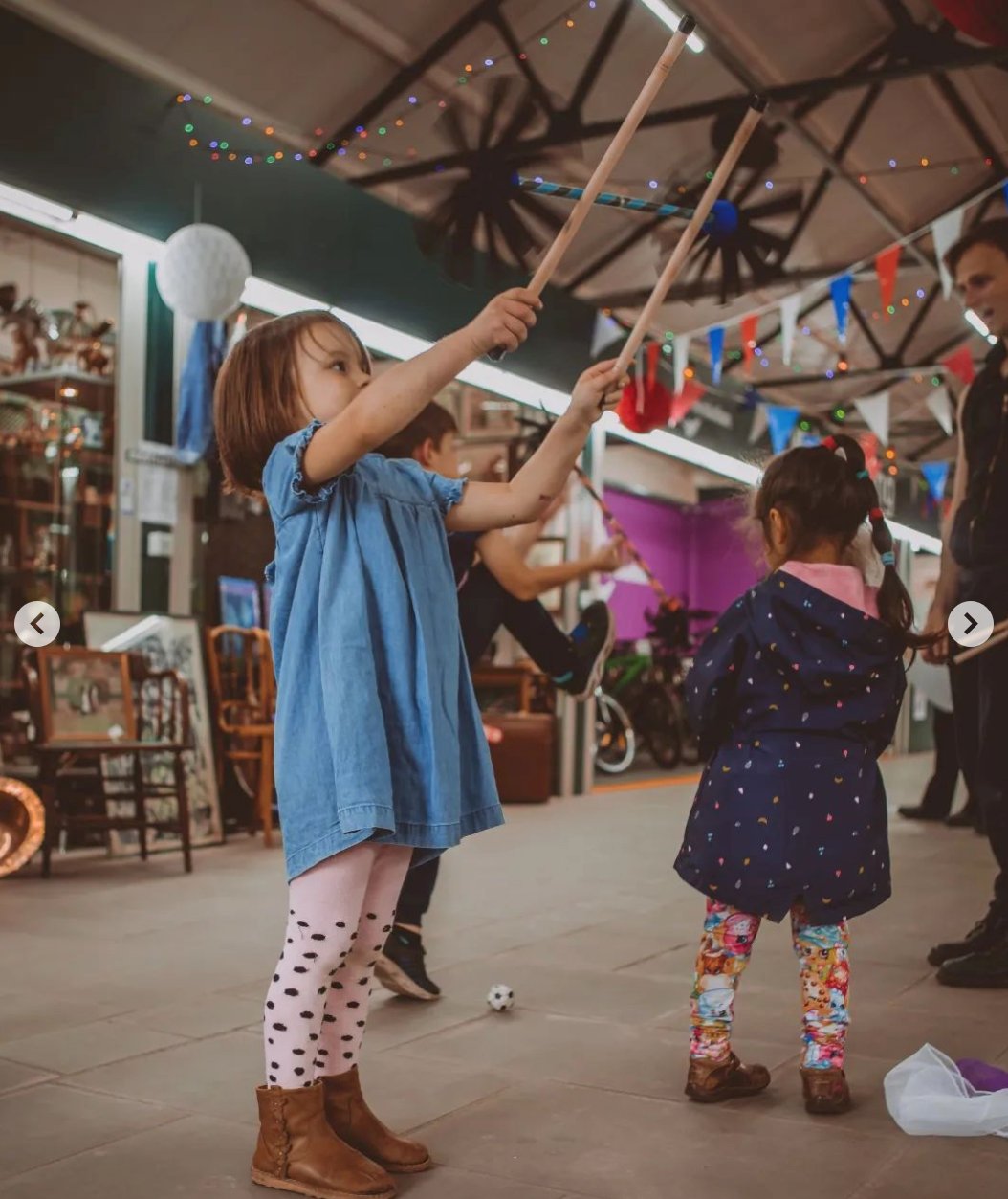 Children practising circus skills with flower sticks in a family workshop.