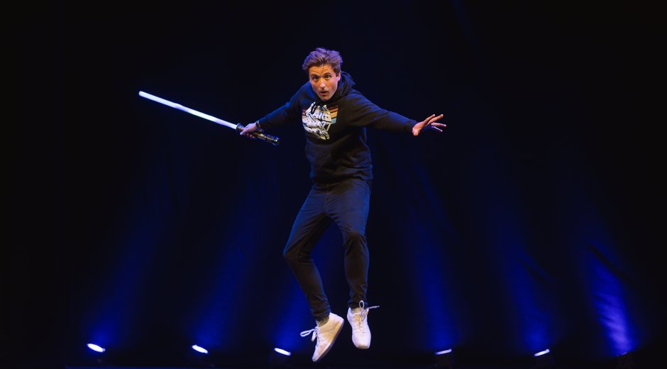 This image shows a person suspended mid-air on a theatre stage, creating a dynamic action pose.