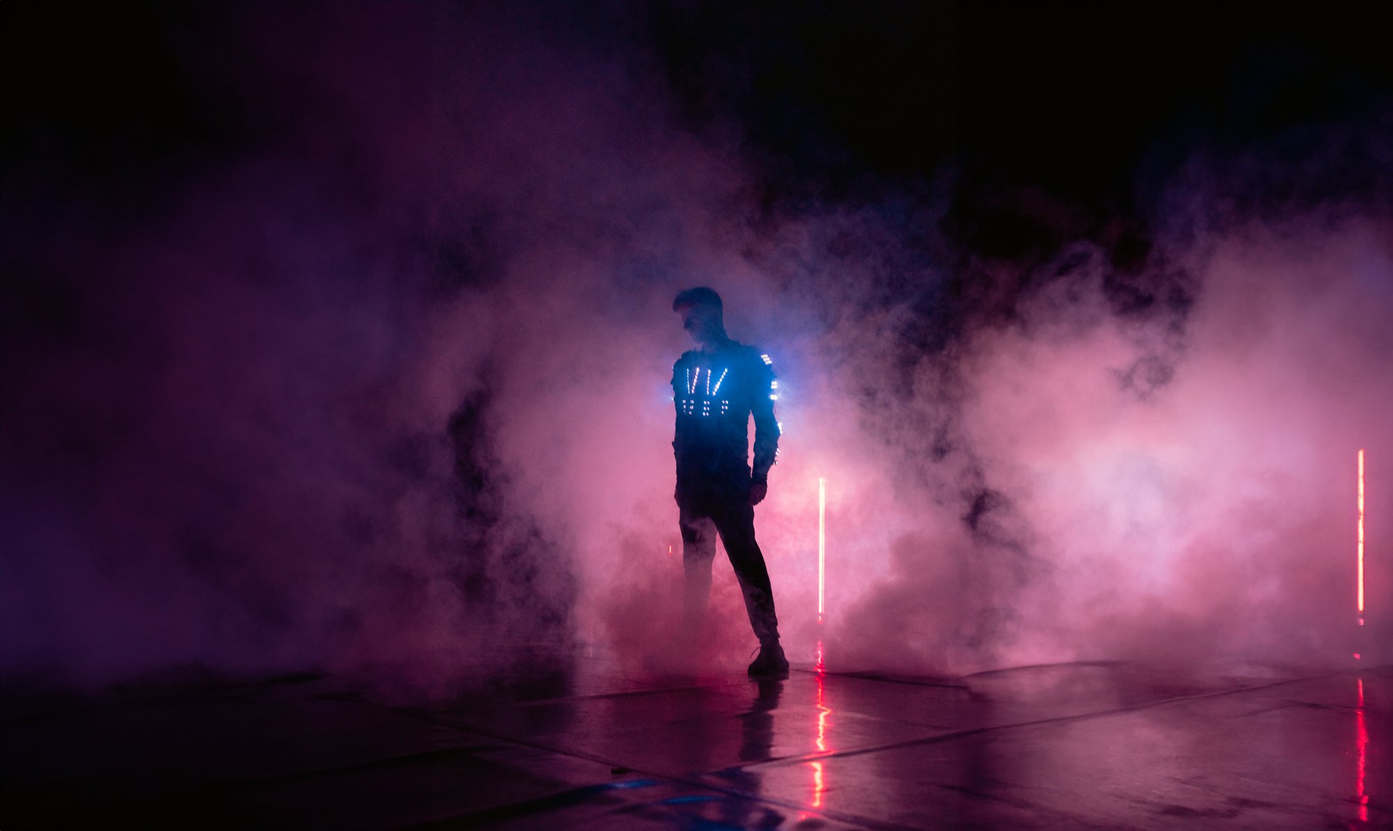 A performer stood in an atmospheric smoky setting with LED lights shining through the smoke