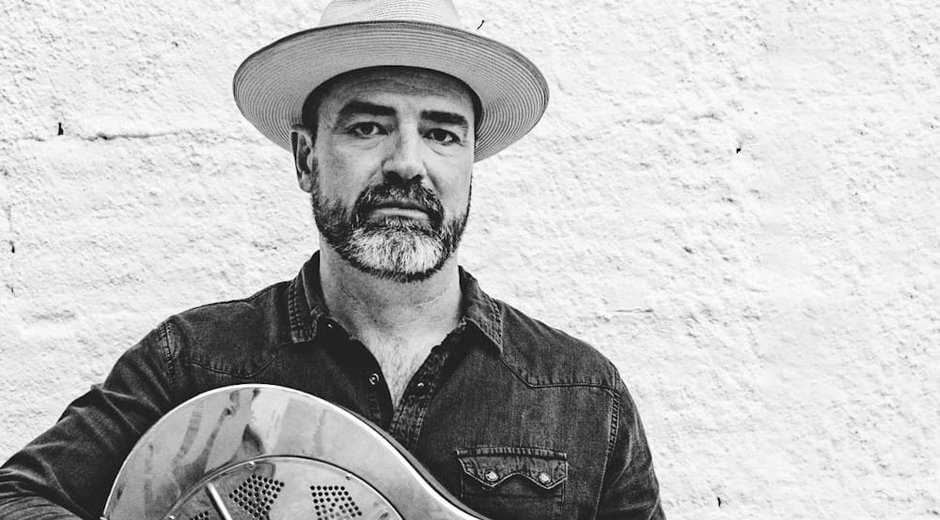 Black and white image of Martin Harley holding a guitar