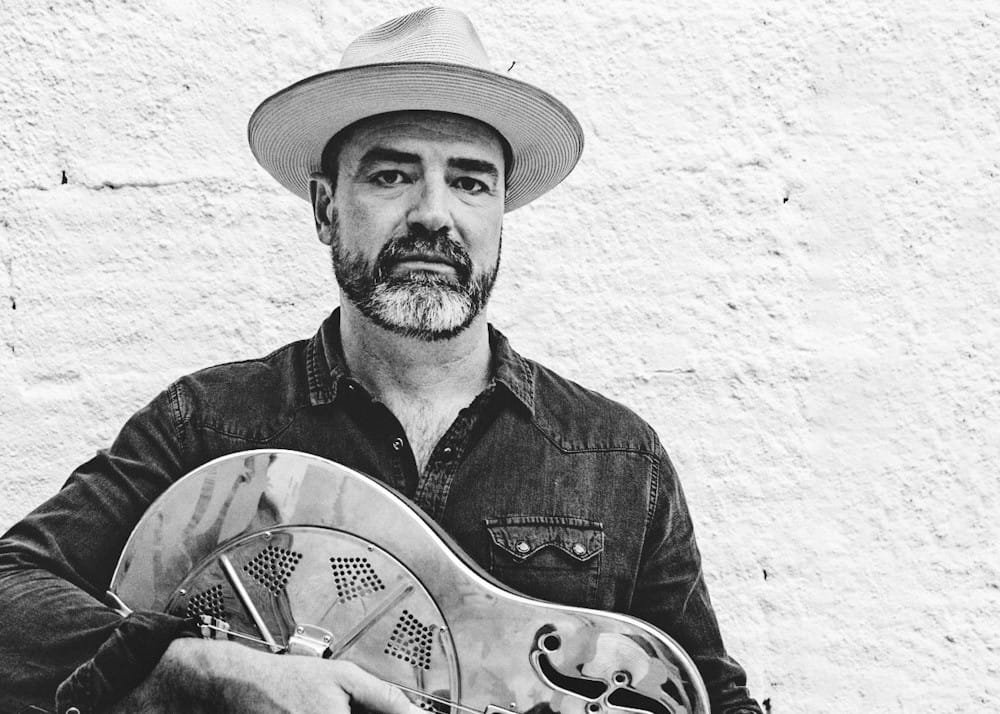 Black and white image of Martin Harley holding a guitar