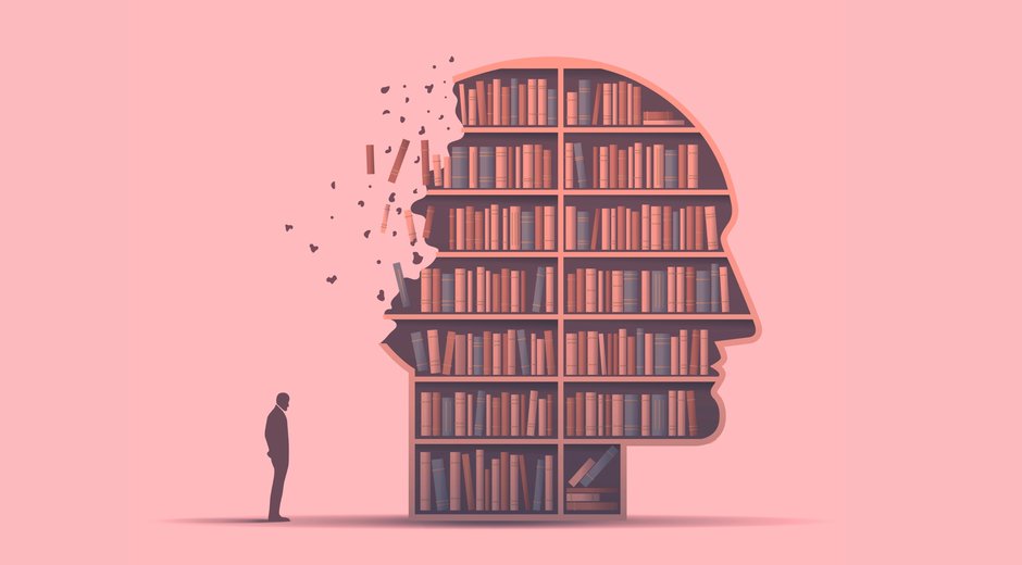 A man stood next to a giant head full of bookshelves