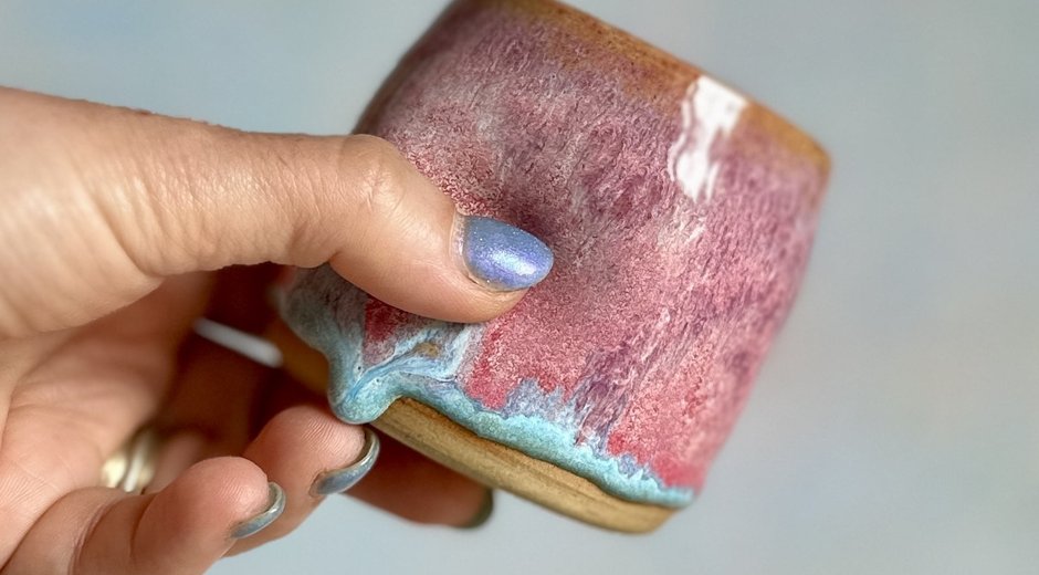 Pink and turquoise glazed pot being squeezed in someone's hand