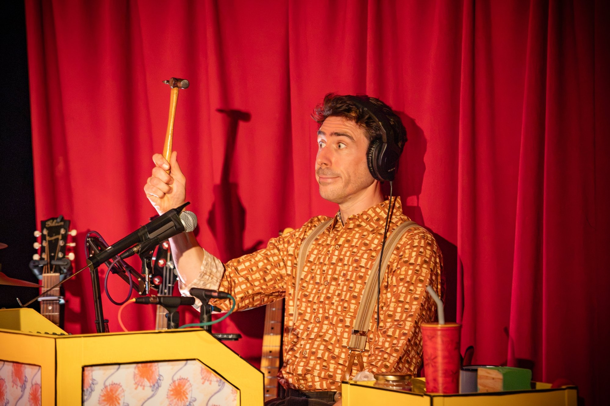 A person smiling and holding up a drumstick in front of percussion