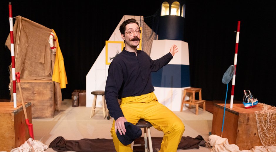 Performer sitting in front of a model of a lighthouse