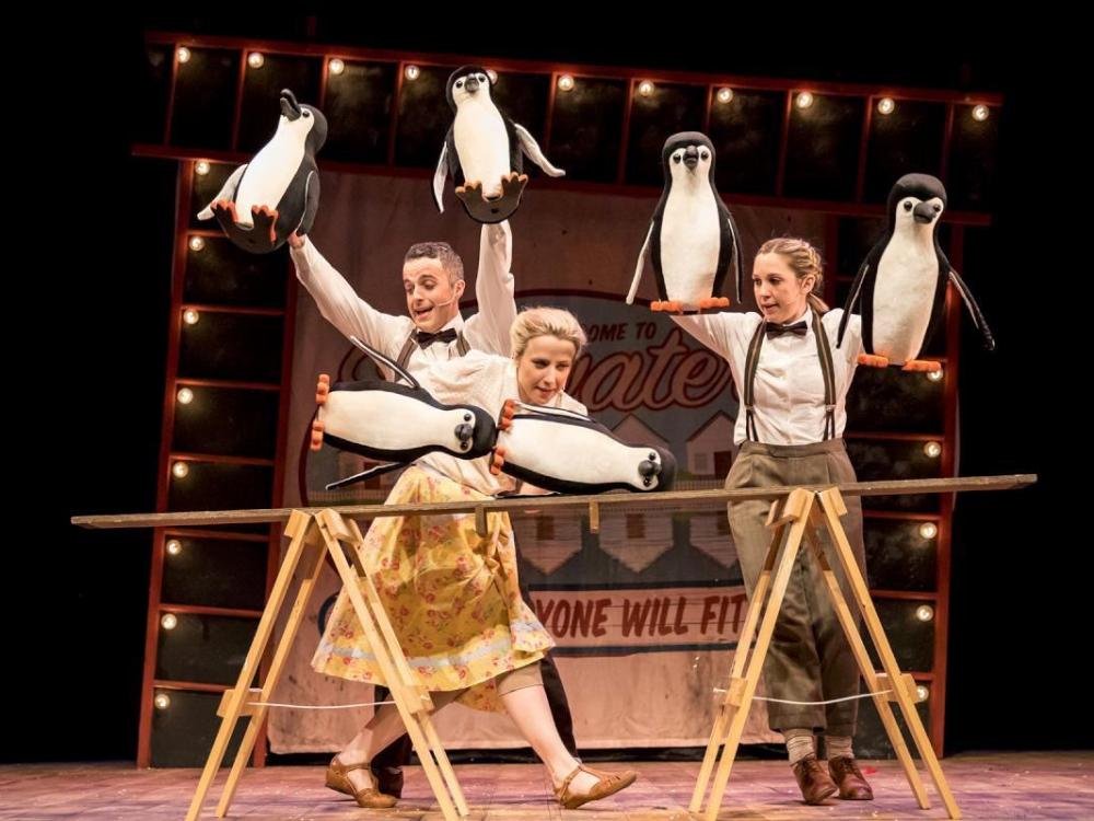 Three people and penguins doing acrobatics